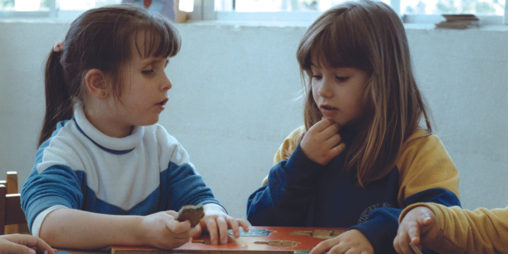 dos niñas, una de ellas es ciega, jugando a encajar piezas en un tablero
