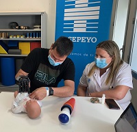 Paciente con mano biónica cambiando los pañales a un muñeco