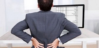 Una persona en un ordenador sufriendo carga física debido a la postura de trabajo