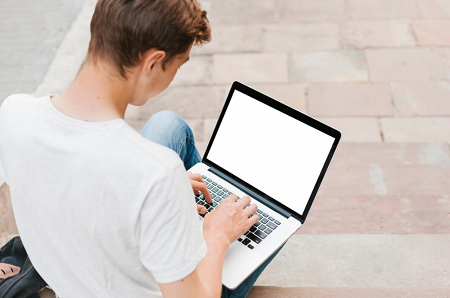 chico joven de espalda usando un ordenador portátil