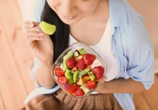 Una persona con un tenedor cogiendo fruta de una copa de la guía alimentación y nutrición
