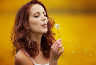 Mujer soplando una flor, ciertas sustancias pueden provocar enfermedad de los pulmones