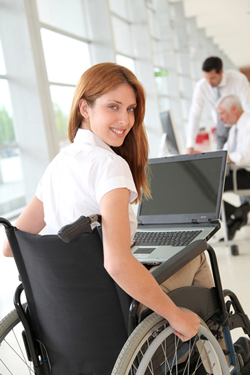 ué es Discapnet, una joven en silla de ruedas en su oficina y con su ordenador en sus piernas