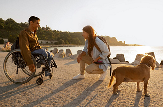 chico en silla de ruedas con su pareja y el perro en la playa