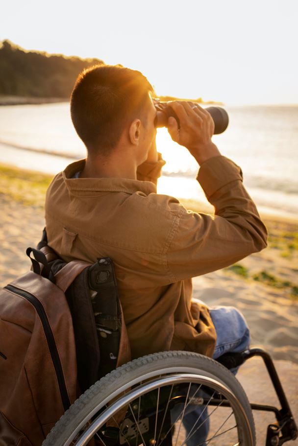 persona en silla de ruedas conservando a través de prismáticos el mar