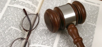 LIOUNDAU. Mazo de un juez y gafas encima de un libro de derechos