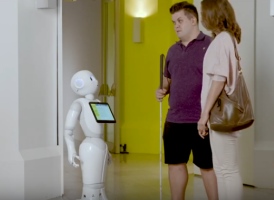 hombre con ceguera y acompañante junto a Paca, referente de robótica asistencial