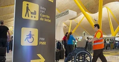 Un operario del Servicio de Asistencia a Personas con Discapacidad o Movilidad Reducida, 'Sin Barreras', de Aena, llevando una silla de ruedas (Fuente: Aena)