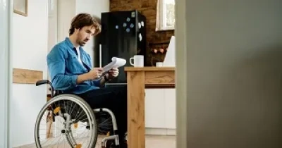 Una persona en silla de ruedas leyendo un documento en su casa (Fuente: Servimedia)