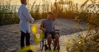 Una persona en silla de ruedas en una playa adaptada con un acompañante (Fuente: Servimedia)