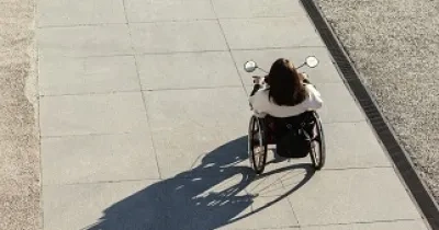 Una persona en silla de ruedas paseando por una calle (Fuente: Servimedia)