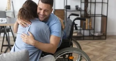 La compañía adjudicataria entrevistará a 14.000 personas que residan en los 1.000 centros seleccionados para el estudio, como podría ser el caso de esta persona en silla de ruedas de la fotografía abrazando a su visitante (Fuente: Servimedia)