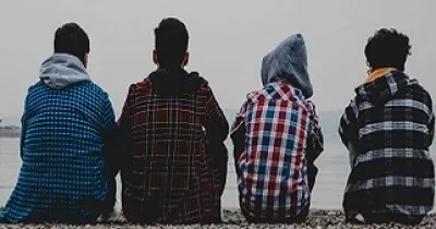 Cuatro jóvenes en riesgo de exclusión social mirando al mar en una playa (Fuente: Fundación Integra)