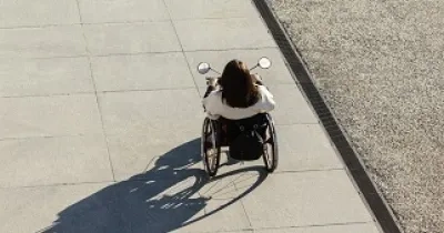 Una persona en silla de ruedas paseando por una calle (Fuente: Servimedia)