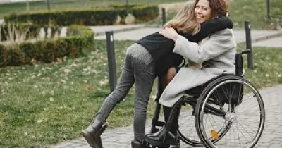 Mujer en silla de ruedas abrazando a una niña, que podría ser su hija (Fuente: Servimedia)