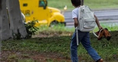 Fotografía de un niño latinoamericano que va a la escuela descalzo por el campo, para el banner de la iniciativa 'Piecitos Colorados' de la Fundación Prosegur
