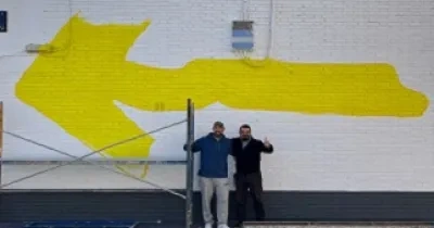 Momento del proceso de realización de la gran Flecha Amarilla del Camino de Santiago, con el grafitero Reyes19 y Antonio Tejada de La Ciudad Accesible (Fuente: La Ciudad Accesible)