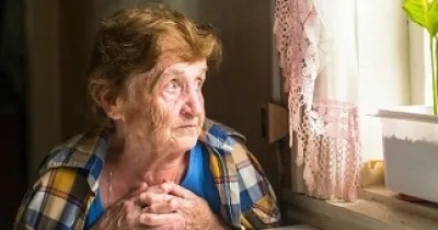 Una mujer mayor mirando sola por la ventana (Fuente: AvisoVoz)