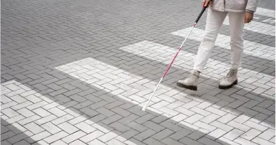 hombre con discapacidad visual andando por un paso de cebra con el baston