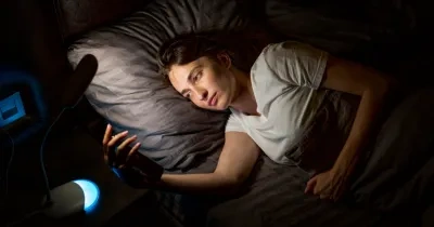 mujer mirando el movil por la noche en la cama a causa del insomnio