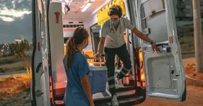 Dos sanitarias bajando de una ambulancia, trasportando una nevera con una donación de un órgano