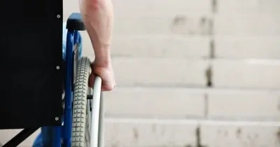 silla de ruedas vista desde la espalda con unas escaleras de fondo