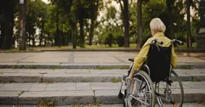 Una persona con movilidad reducida (PMR) y en silla de ruedas ante una escalera (Fuente: Rehatrans)