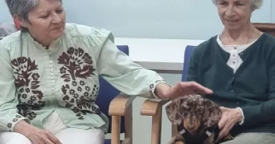Dos personas mayores junto a un perro en una sesión de terapia asistida con animales (Fuente: Neurovida)
