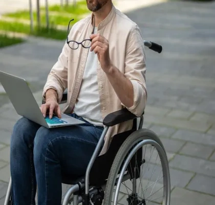 Un estudiante en silla de ruedas consulta su ordenador | Foto de 123RF/zinkevych