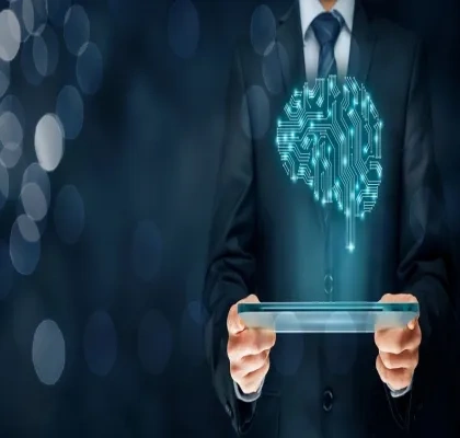  Un hombre de negocios con un traje oscuro sostiene una tableta digital. Sobre el pecho del hombre, se proyecta una imagen de un cerebro humano formado por circuitos electrónicos, simbolizando la inteligencia artificial o el aprendizaje automático. El fondo está lleno de puntos de luz desenfocados, creando un ambiente tecnológico y futurista.