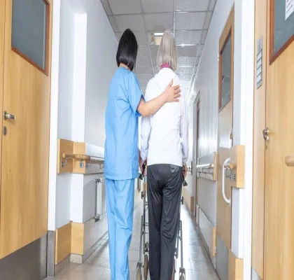 médico andando con una persona mayor por pasillos de una residencia