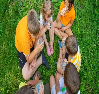 Seis niños sentados en el césped en corrillo 