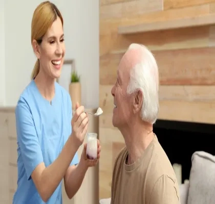 una cuidadora dando un yogurt a un anciano