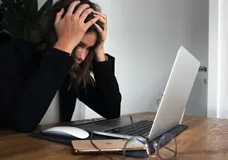 mujer con las manos en la cabeza mirando su pórtatil