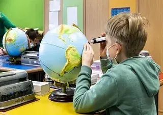 estudiante con una discapacidad visual, tocando un globo terráqueo