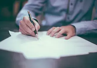 hombre firmando un papel