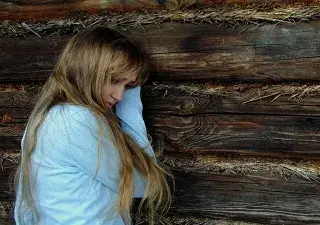 chica joven triste apoyada en la pared