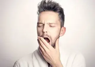 Hombre bostezando, tapándose la boca con la mano