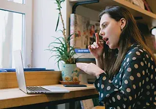 Chica delante de portátil hablando mediante lengua de signos con su interlocutor