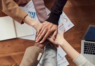 Manos superpuestas unas sobre las otras en señal de colaboración