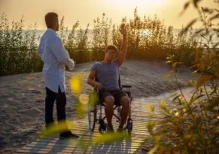 Una persona en silla de ruedas en una playa adaptada con un acompañante (Fuente: Servimedia)