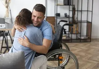 La compañía adjudicataria entrevistará a 14.000 personas que residan en los 1.000 centros seleccionados para el estudio, como podría ser el caso de esta persona en silla de ruedas de la fotografía abrazando a su visitante (Fuente: Servimedia)