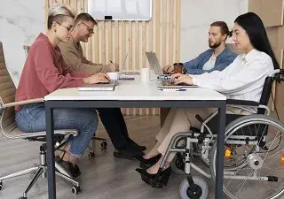 Un grupo de compañeros, una de ellas en silla de ruedas, trabajando (Fuente: Servimedia)