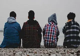 Cuatro jóvenes en riesgo de exclusión social mirando al mar en una playa (Fuente: Fundación Integra)