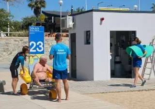 persona mayor dependiente siendo ayudado por personal de ILUNION para acceder en una silla anfibia a la playa