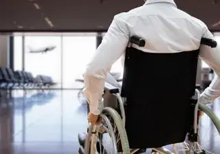 persona en silla de ruedas mirando a un avión que despega al fondo