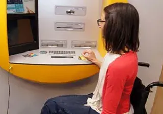 Una persona en silla de ruedas en un cajero automático accesible, al dar luz verde al proyecto de ley para adaptarlos junto al 112 y otros servicios (Fuente: Discapnet)
