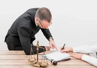 Dos personas escriben junto a símbolos que representan la justicia (Fuente: Servimedia)