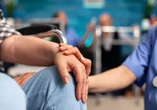 Un asistente sanitario reconforta a una persona sentada en una silla (Fuente: Servimedia)