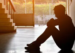 Una persona joven sentada en el suelo con depresión (Fuente: SHUTTERSTOCK)